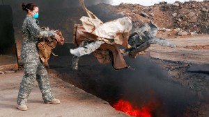 Senior Airman Frances Gavalis tosses unserviceable uniform items into a burn pit March 10 at Balad Air Base, Iraq. Military uniform items turned in must be burned to ensure they cannot be used by opposing forces. Photo by (U.S. Air Force photo/Senior Airman Julianne Showalter