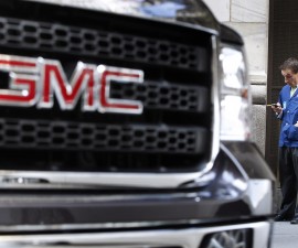 A GMC vehicle is seen parked in front of a trader standing outside of the New York Stock Exchange on Nov. 18, 2010. On Monday, GM announced a $5 billion stock buyback, part of bigger trend in corporate America, argues entrepreneur Nick Hanauer, that's threatening the American economy. Photo by REUTERS/Shannon Stapleton.