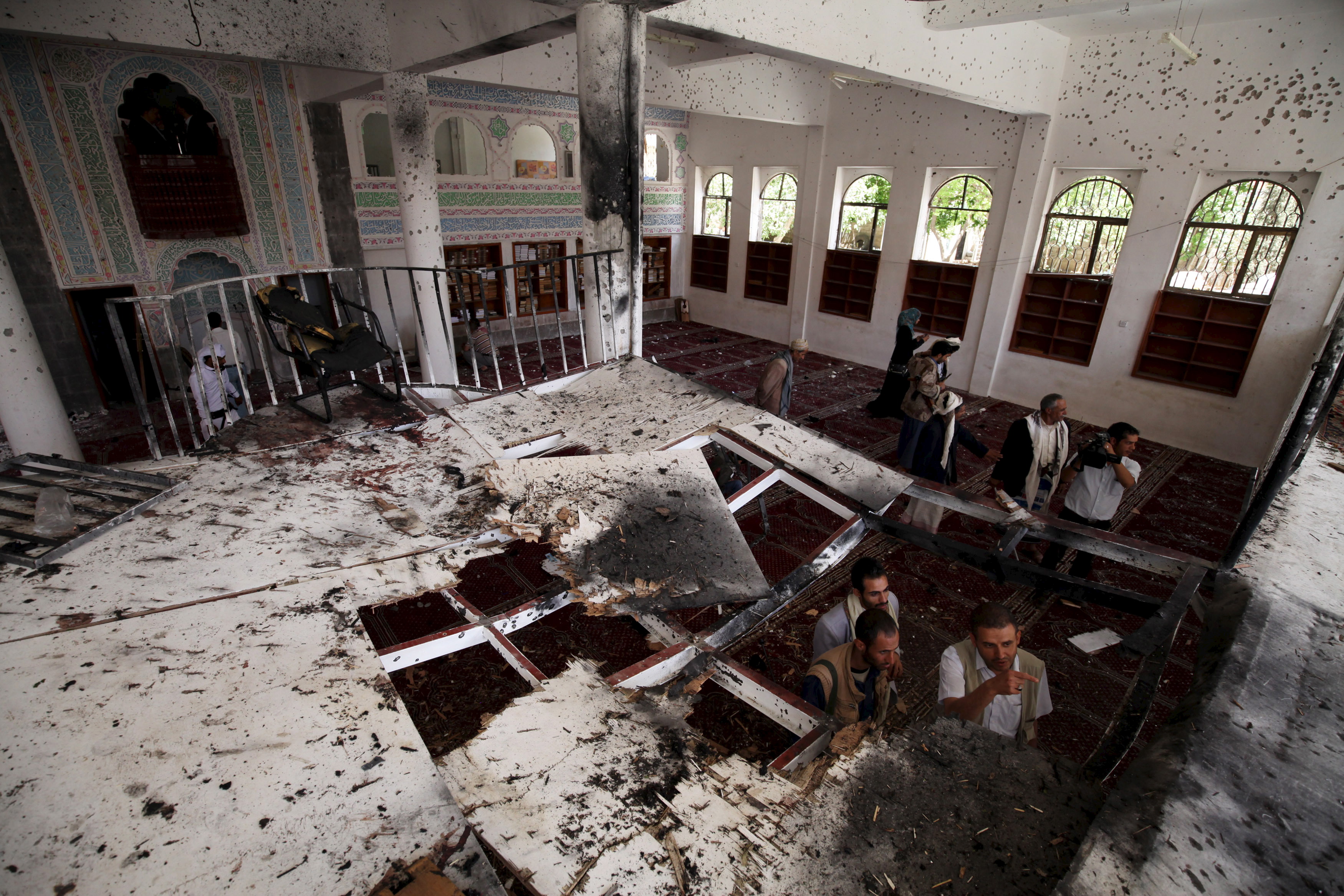 People look inside a damaged mosque after Friday's suicide bomb attack in Sanaa March 22, 2015. Suicide bombers killed at least 137 worshippers and wounded hundreds more during Friday prayers at two mosques in the Yemeni capital Sanaa, in coordinated attacks claimed by Islamic State. Photo by Mohamed al-Sayaghi/Reuters
