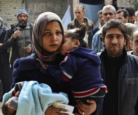 Residents queue up to receive humanitarian aid at the Palestinian refugee camp of Yarmouk, in Damascus