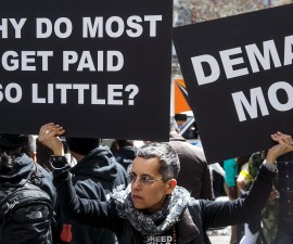 A protester holds signs aloft in front of a McDonald's restaurant during demonstrations asking for higher wages in the Manhattan borough of New York City
