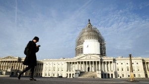 A woman checks her smartphone as she walks past the U.S. Capitol in Washington December 4,  2014.  U.S. President Barack Obama voiced optimism on Wednesday that a government shutdown can be avoided in coming weeks, pointing to comments from Republican leaders of Congress who oppose a budget showdown. Photo by Kevin Lamarque/Reuters
