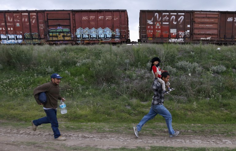A Salvadoran father carries his son while running next to another immigrant as they try to board a train heading to the Mexican-U.S. border, in Huehuetoca, near Mexico City, June 1, 2015. An increasing number of Central Americans are sneaking across Mexico's border en route to the United States, but many of them don't end up making it very far. Picture taken June 1, 2015. Photo by Edgard Garrido/Reuters