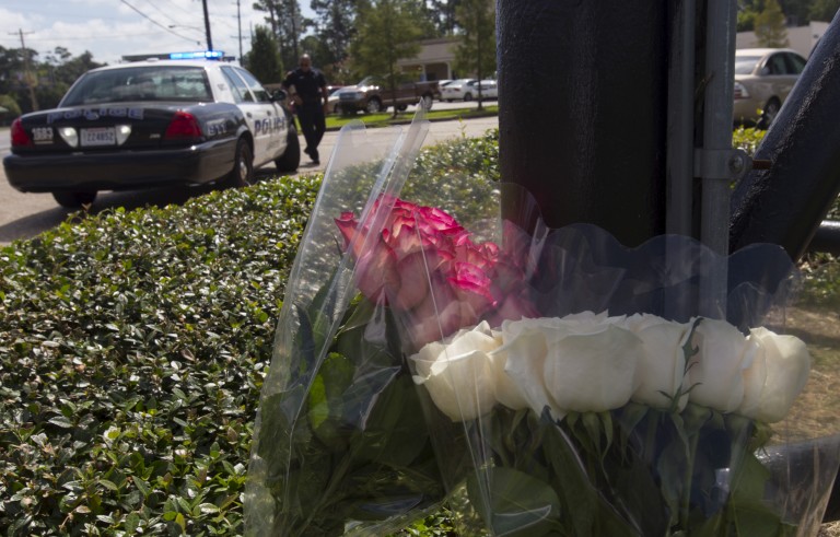 A police officer stands at the entrance to a movie theatre, near flowers left for victims of a Thursday night shooting, in the theatre in Lafayette, Louisiana July 24, 2015. John Russell Houser, an Alabama drifter, opened fire inside the crowded movie theater, killing two women, police said, in the latest act of random gun violence to shock the United States. REUTERS/Lee Celano - RTX1LOGL