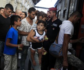 Watched by Hungarian police, refugees enter a regional train supposed to carry them to a nearby refugee camp at a railways station in Budapest, Hungary September 2, 2015. Hundreds of migrants protest in front of Budapest's Keleti Railway Terminus for a second straight day on Wednesday, shouting "Freedom, freedom!" and demanding to be let onto trains bound for Germany from a station that has been closed to them by Hungarian riot police officers. REUTERS/Bernadett Szabo - RTX1QSF3