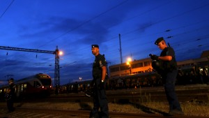 Police guard a train full of refugees stuck in a stalemate as they refuse to obey police and get off at the station, fearing they would be put up in a nearby refugee camp in Bicske, Hungary, September 3, 2015. France and Germany said European countries must be required to accept their shares of refugees, proposing what would potentially be the biggest change to the continent's asylum rules since World War Two. Europe's worst refugee crisis since the Yugoslav wars of the 1990s has strained the European Union's asylum system to breaking point, dividing its 28 nations and feeding the rise of right-wing populists. REUTERS/Laszlo Balogh - RTX1QZD1