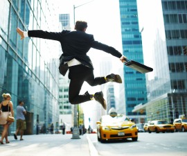 Businessman jumping for joy on city street. Credit: Andy Ryan/Getty Images