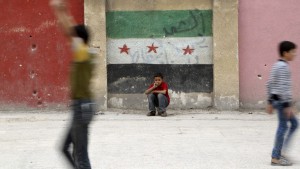 Boys play at a school's playground as one of them sits in front of a wall painted with an opposition flag in the rebel-controlled area of Aleppo's Seif al-Dawla, Syria October 25, 2015. REUTERS/Hosam Katan      EDITORIAL USE ONLY. NO RESALES. NO ARCHIVE - RTX1T67Z