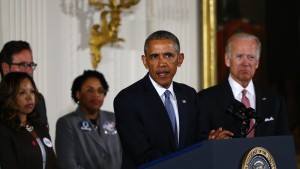 U.S. President Barack Obama stands with Vice President Joe Biden (R) and family members of shooting victims while delivering a statement on steps the administration is taking to reduce gun violence in the East Room of the White House in Washington January 5, 2016. REUTERS/Carlos Barria - RTX215G3