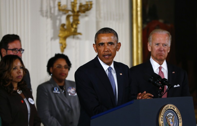 U.S. President Barack Obama stands with Vice President Joe Biden (R) and family members of shooting victims while delivering a statement on steps the administration is taking to reduce gun violence in the East Room of the White House in Washington January 5, 2016. REUTERS/Carlos Barria - RTX215G3