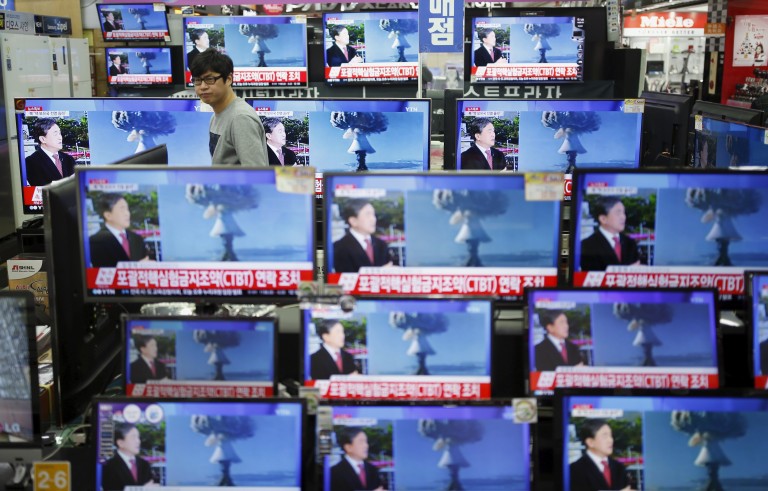 A sales assistant watches TV sets broadcasting a news report on North Korea's nuclear test, in Seoul, January 6, 2016. Photo by Kim Hong-Ji/Reuters