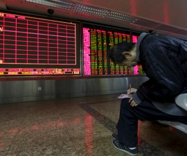 An investor takes notes of stock information in front of an electronic board at a brokerage house in Beijing, China, January 8, 2016.  REUTERS/Jason Lee        TPX IMAGES OF THE DAY      - RTX21HN4