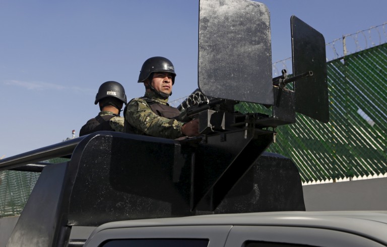 Mexican soldiers stand guard atop a vehicle on a street awaiting the arrrival of recaptured drug lord Joaquin "El Chapo" Guzman at the Navy's airstrip in Mexico City, Mexico January 8, 2016. Mexico recaptured the world's most notorious drug lord Guzman with U.S. help in a violent standoff on Friday, six months after he humiliated President Enrique Pena Nieto by tunnelling out of a maximum security prison. Guzman, head of the powerful Sinaloa Cartel whom Pena Nieto first caught in February 2014, was captured in an early morning raid that killed five in the city of Los Mochis in the drug baron's native state of Sinaloa in northwest Mexico. REUTERS/Henry Romero - RTX21L8K
