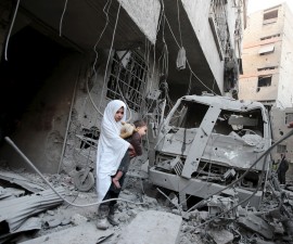 A girl carrying a baby inspects damage in a site hit by what activists said were airstrikes carried out by the Russian air force in the town of Douma, eastern Ghouta in Damascus, Syria January 10, 2016. REUTERS/Bassam Khabieh      TPX IMAGES OF THE DAY      - RTX21RG6
