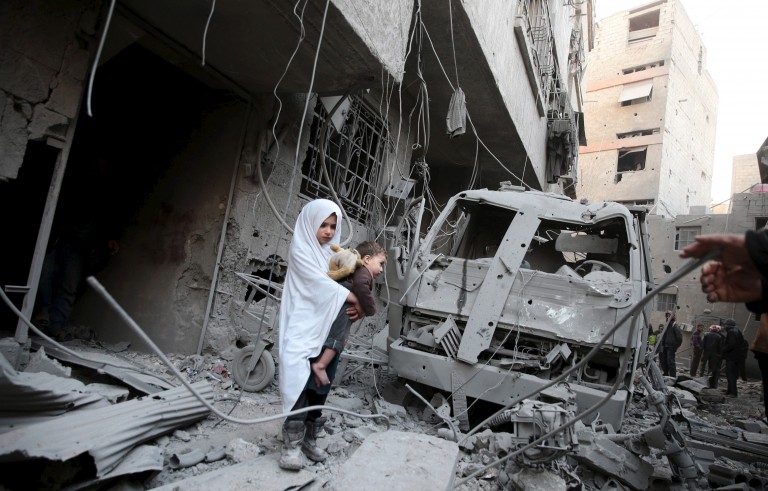 A girl carrying a baby inspects damage in a site hit by what activists said were airstrikes carried out by the Russian air force in the town of Douma, eastern Ghouta in Damascus, Syria January 10, 2016. REUTERS/Bassam Khabieh      TPX IMAGES OF THE DAY      - RTX21RG6