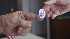 Poll worker Kenny Smith hands a sticker to a voter on Super Tuesday in Stillwater, Oklahoma March 1, 2016. REUTERS/Nick Oxford - RTS8U8T