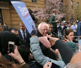 U.S. Democratic presidential candidate Bernie Sanders greets audience members at a campaign rally on the street outside his childhood home (rear) in Brooklyn, New York, New York April 8, 2016. REUTERS/Brian Snyder - RTSE875