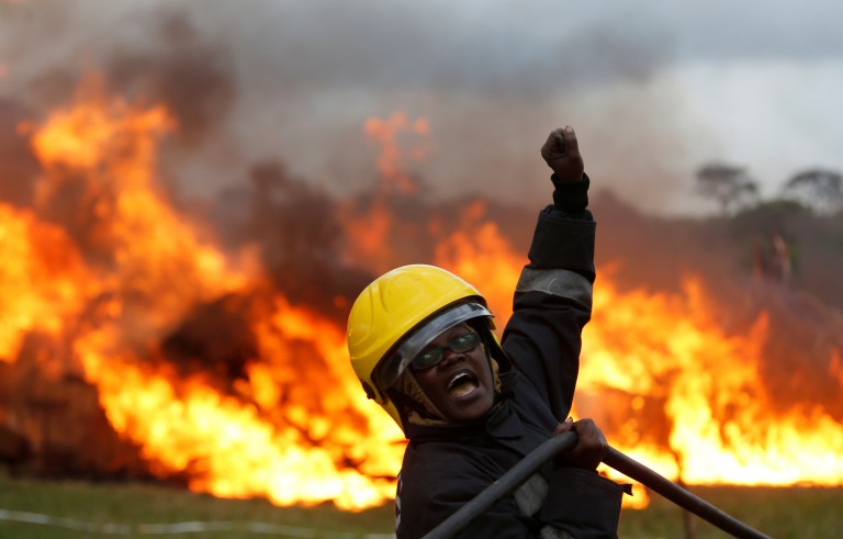A member of the fire brigade shouts as she and other members control the burning of an estimated 105 tonnes of Elephant tusks confiscated ivory from smugglers and poachers at the Nairobi National Park near Nairobi, Kenya, April 30, 2016. REUTERS/Thomas Mukoya - RTX2C948