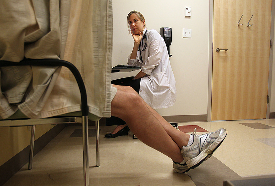A doctor talks to a patient behind a curtain