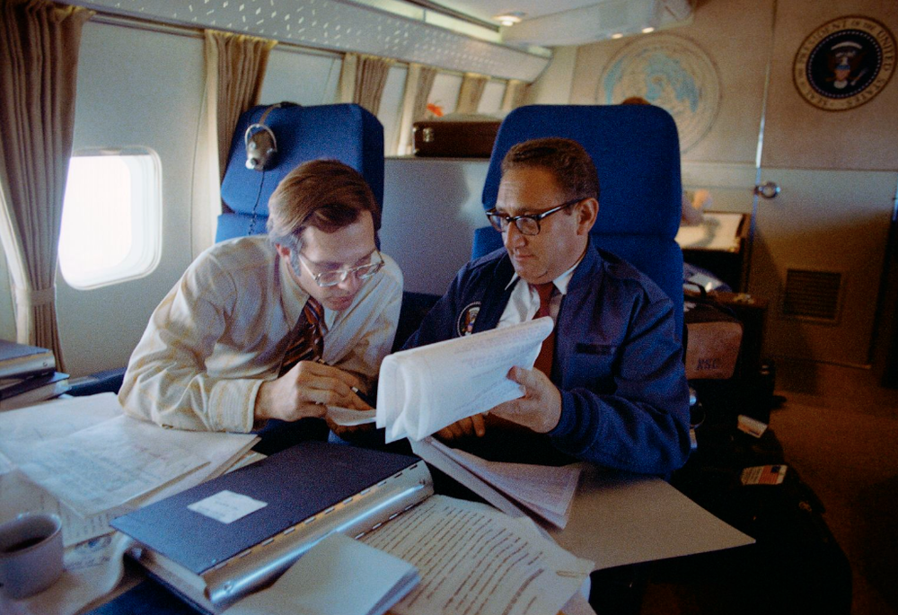 Henry Kissinger shows papers to aide Winston Lord aboard Air Force One in 1972. National Archives and Records Administration. Hero image.png