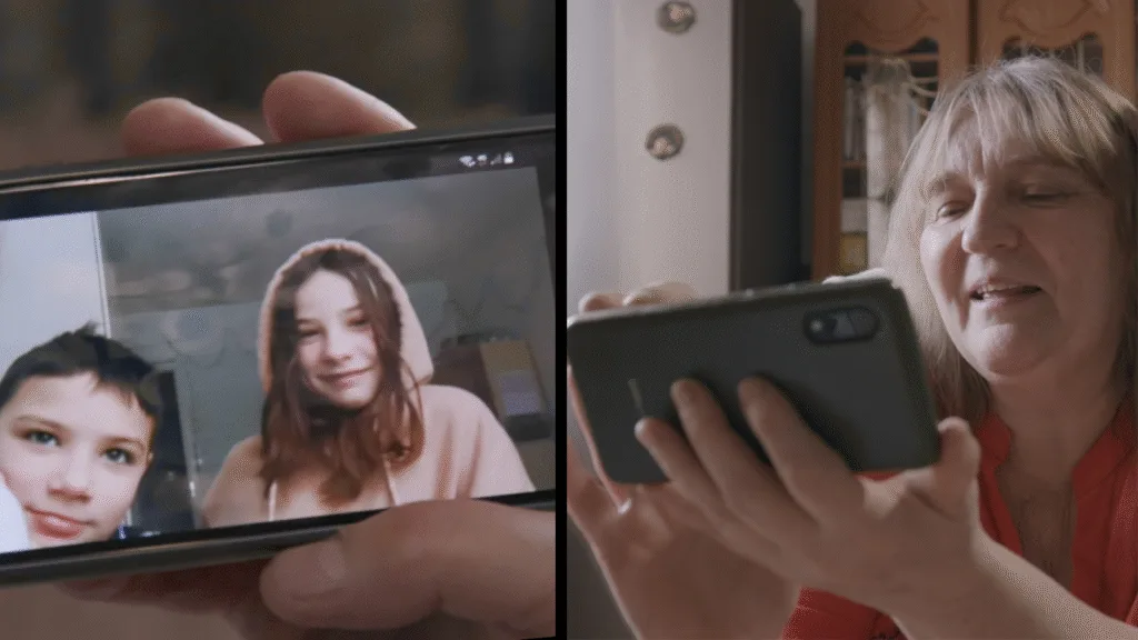 A composite of two photos, one of a woman looking at her phone, and one of two children showing up on the phone screen in a video call.