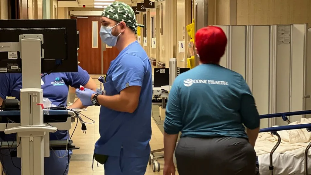 Three staff members stand in a hallway in Moses Cone Health ER.