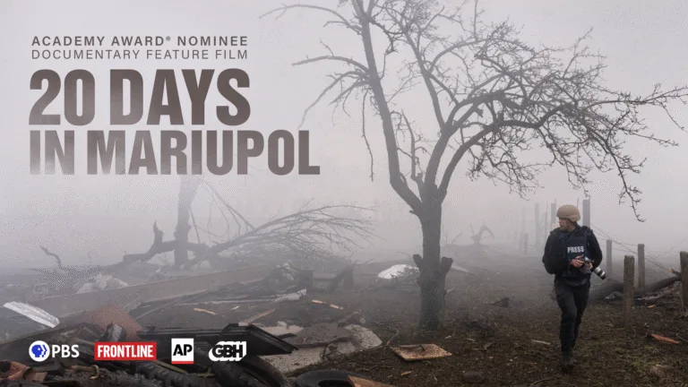 Photographer Evgeniy Maloletka, wearing a press vest and holding a camera in his hands, walks by rubble from the aftermath of a Russian attack in a foggy area in Mariupol, Ukraine. On the left the text reads Academy Award Nominee, Documentary Feature Film, 20 Days in Mariupol. PBS, FRONTLINE, AP and GBH logos are at the bottom of the graphic.