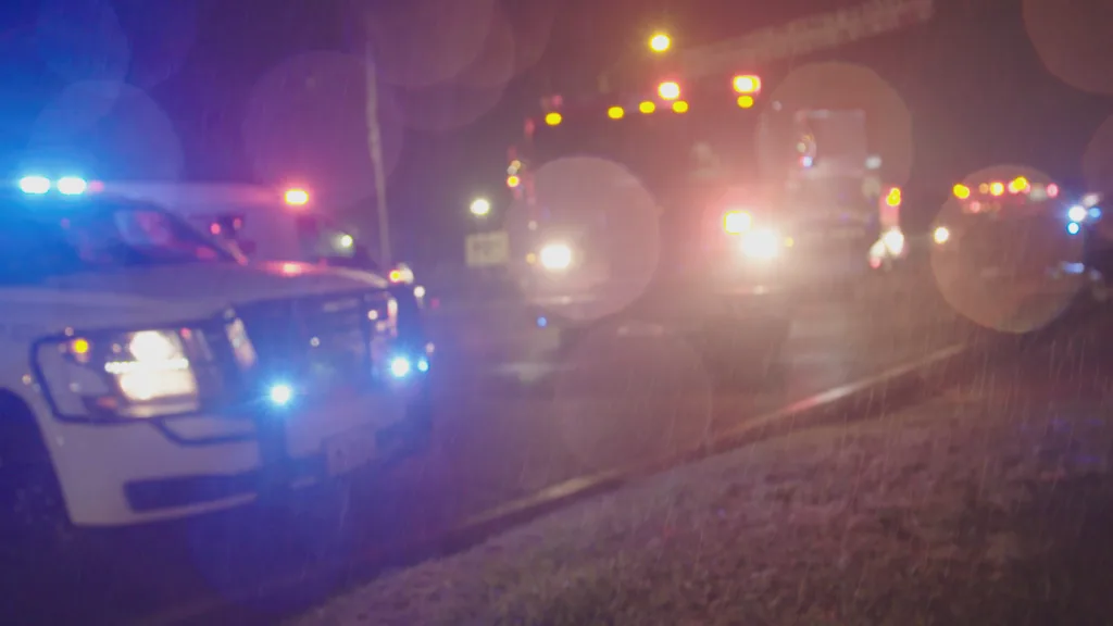 Police car and vehicle lights out of focus at night time in the rain.