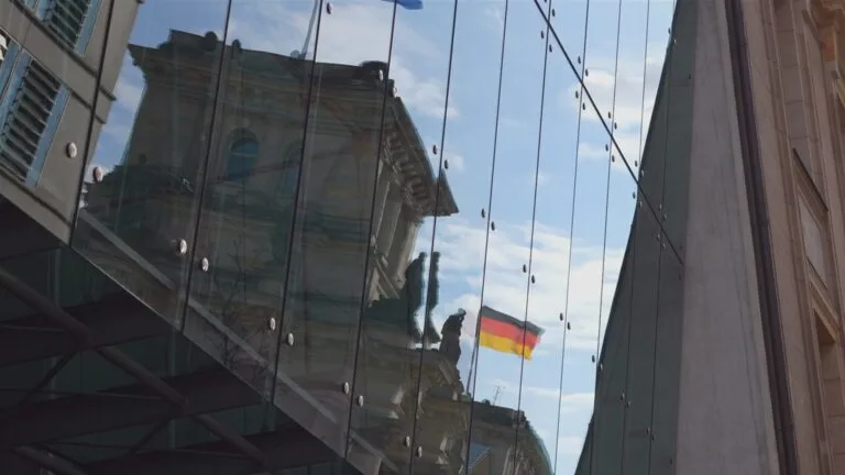 The German flag reflected in a building's glass facade.