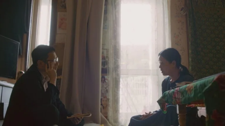 Kim Tong-hyung sits across from a Korean adoptee and holds a notepad in his hand.