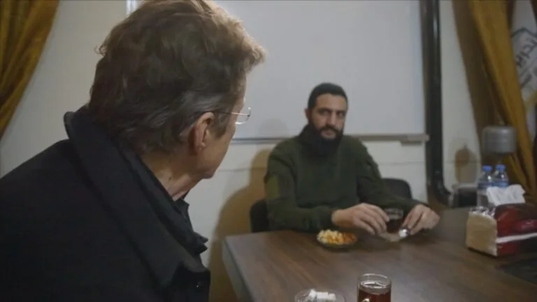 Martin Smith sits at a table with jihadist-turned-statesman Ahmad al-Sharaa.
