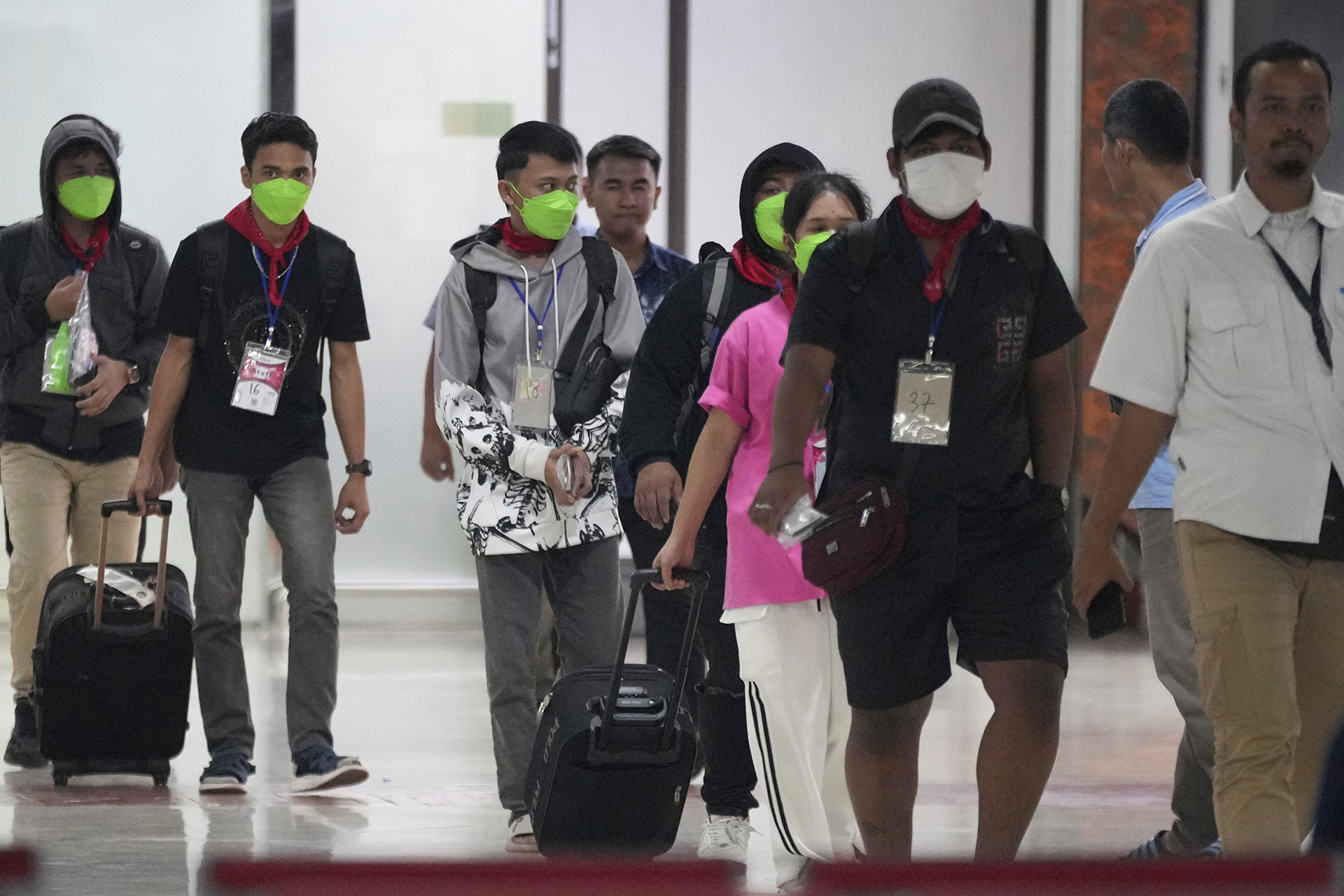 People, some wearing masks and pulling suitcases, walk in an airport in Indonesia.