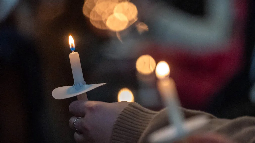 Close-up of hands holding lit candles.