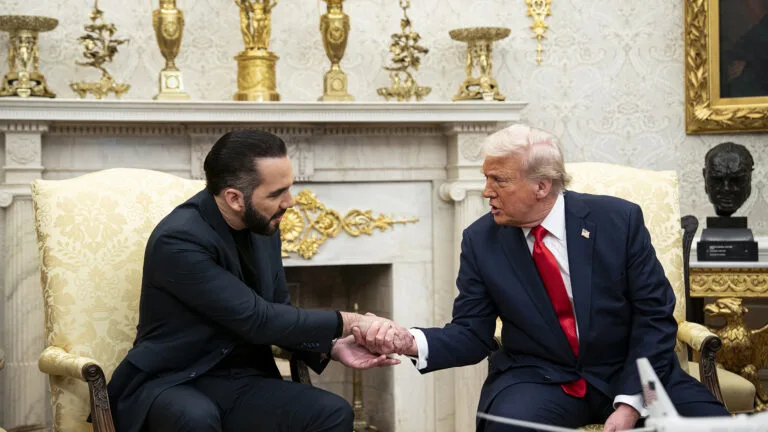 Nayib Bukele sits on a chair on the left, shaking hands with Donald Trump who sits on the right in an ornately decorated room.