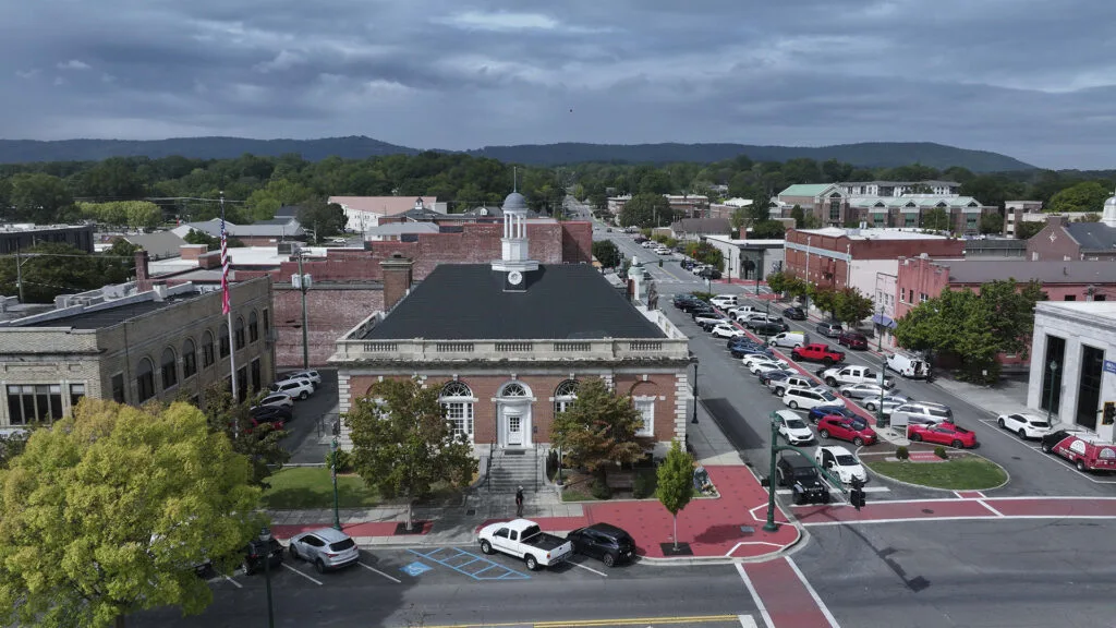 An aerial view of brick buildings and parking spaces in a small downtown area.