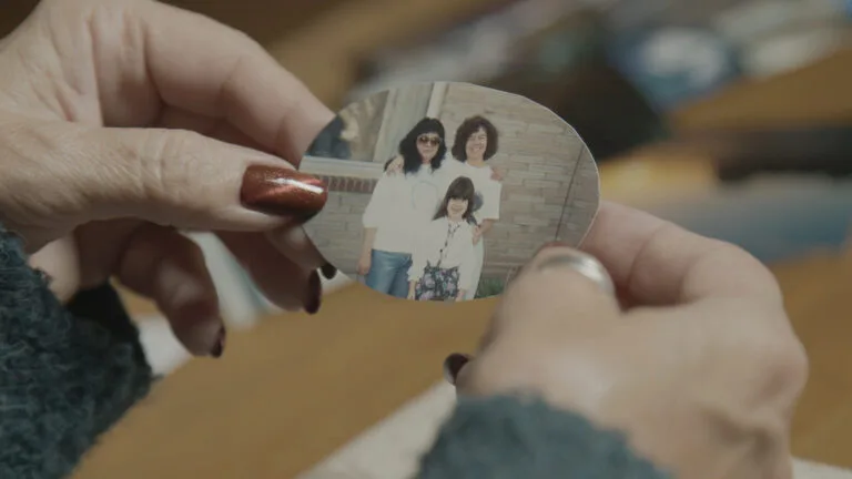 Two hands hold a photo cut into a circular shape that shows two women and a child.