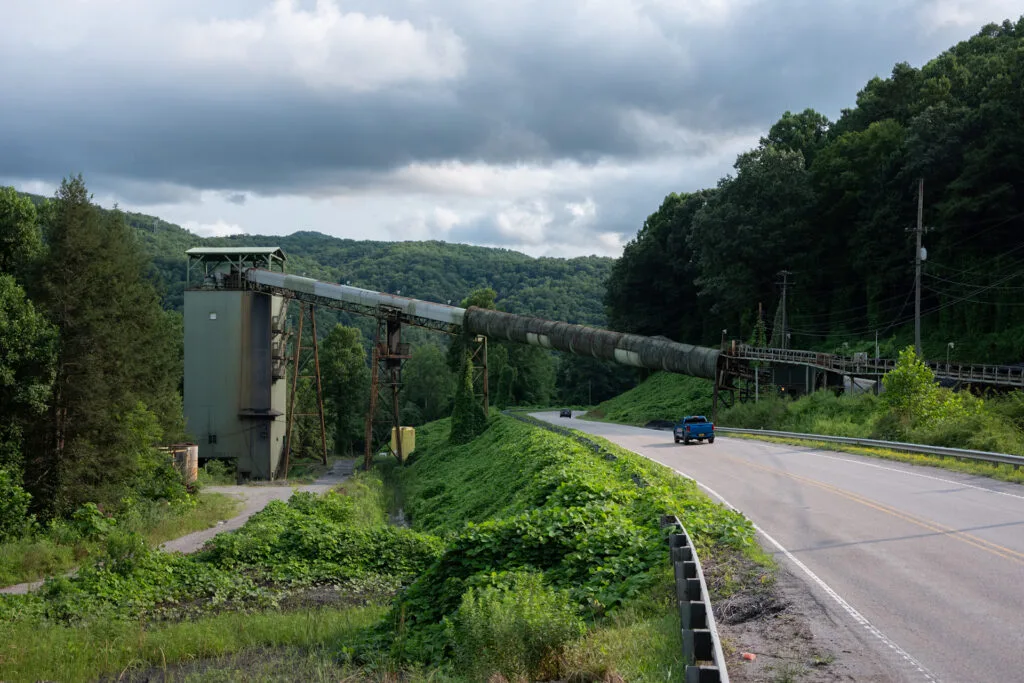 A truck drives on a road that has a structure like a ramp hanging over it.