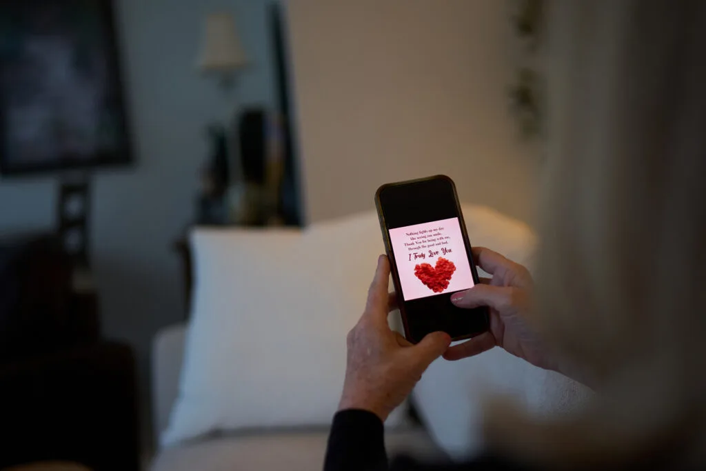 Someone holding a phone that has a graphic showing a heart and the words "I truly love you."