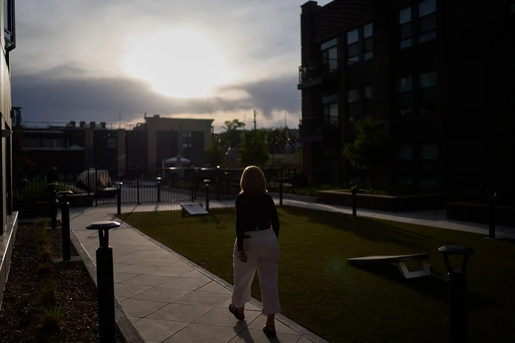 A woman walking on a stone walkway outside as the sun hands low.