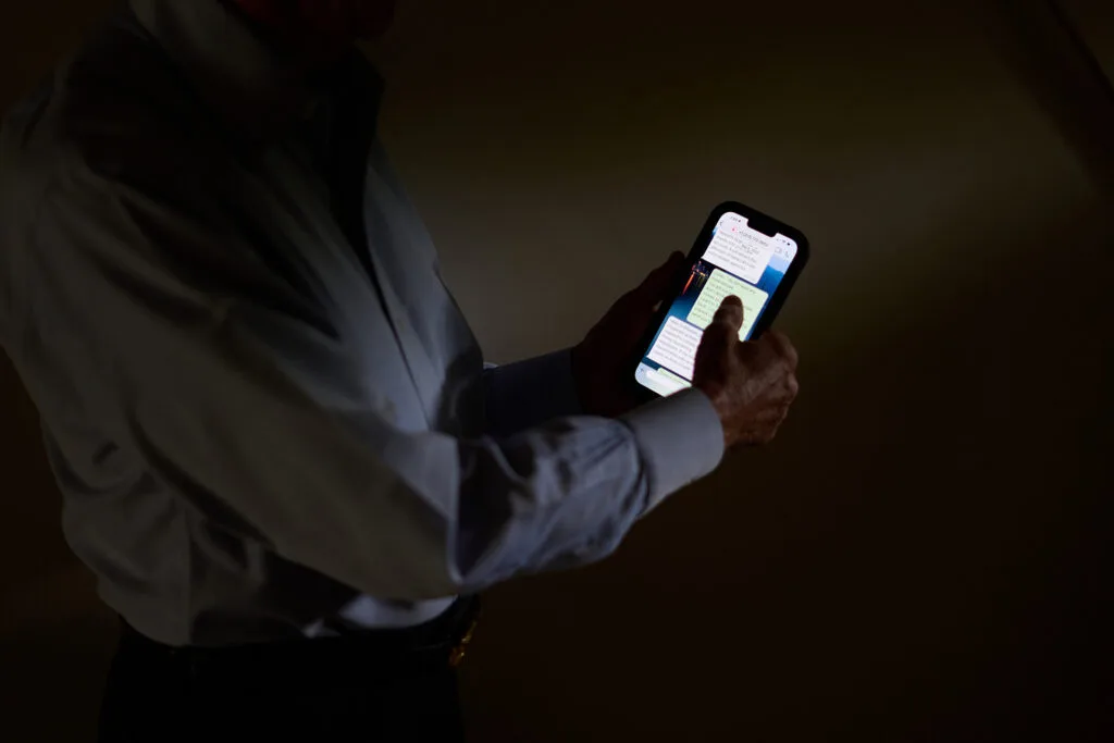 A person in a darkened room holds a phone showing messages.