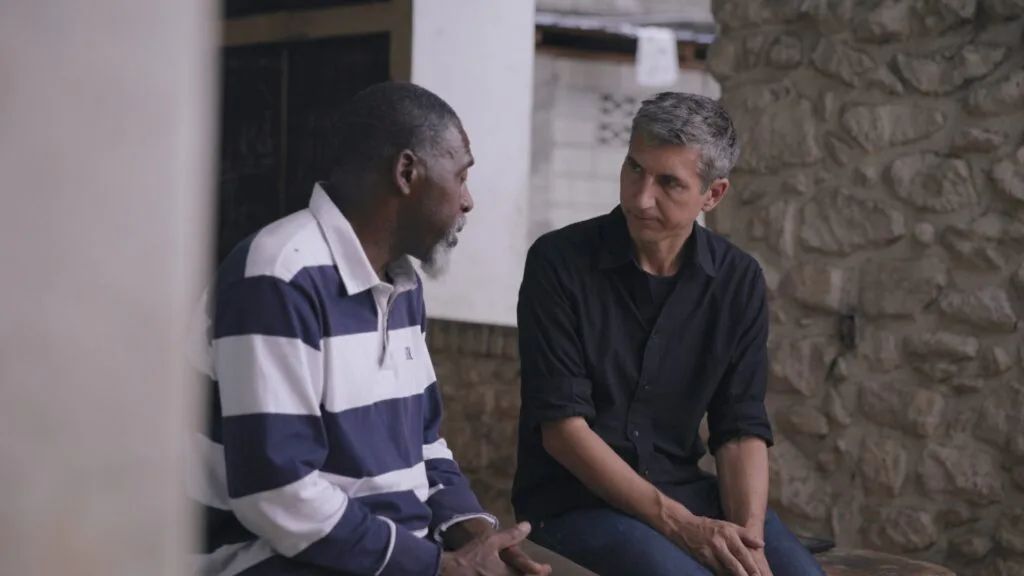 Correspondent Sebastian Walker (R) talks with a man (L) whose daughter was taken hostage in an August 2026 massacre in Kenscoff, Haiti.