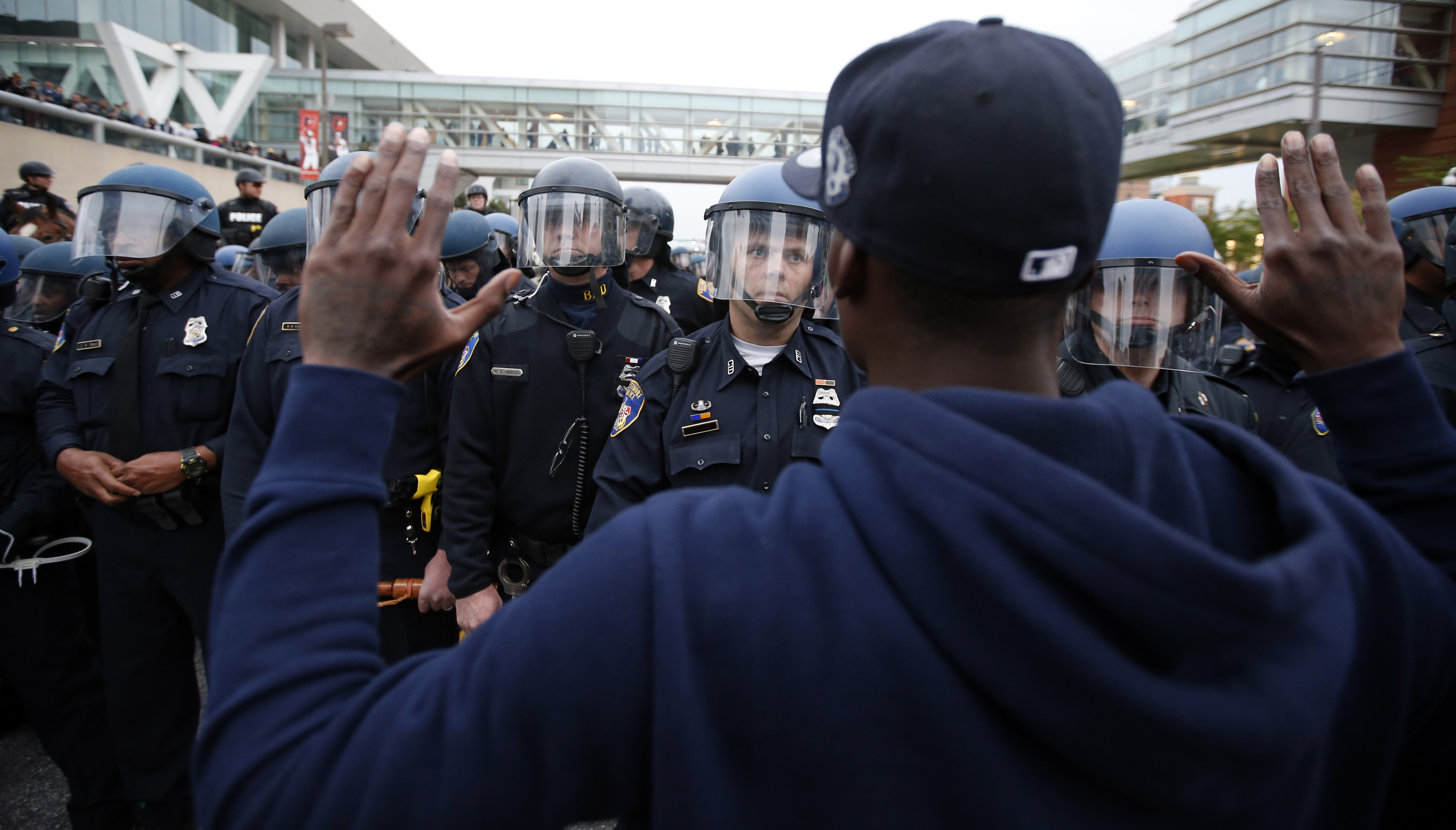 A man holds his hands up in front of a line of helmeted police after a march to City Hall for Freddie Gray, Saturday, April 25, 2015 in Baltimore. (AP Photo/Alex Brandon)