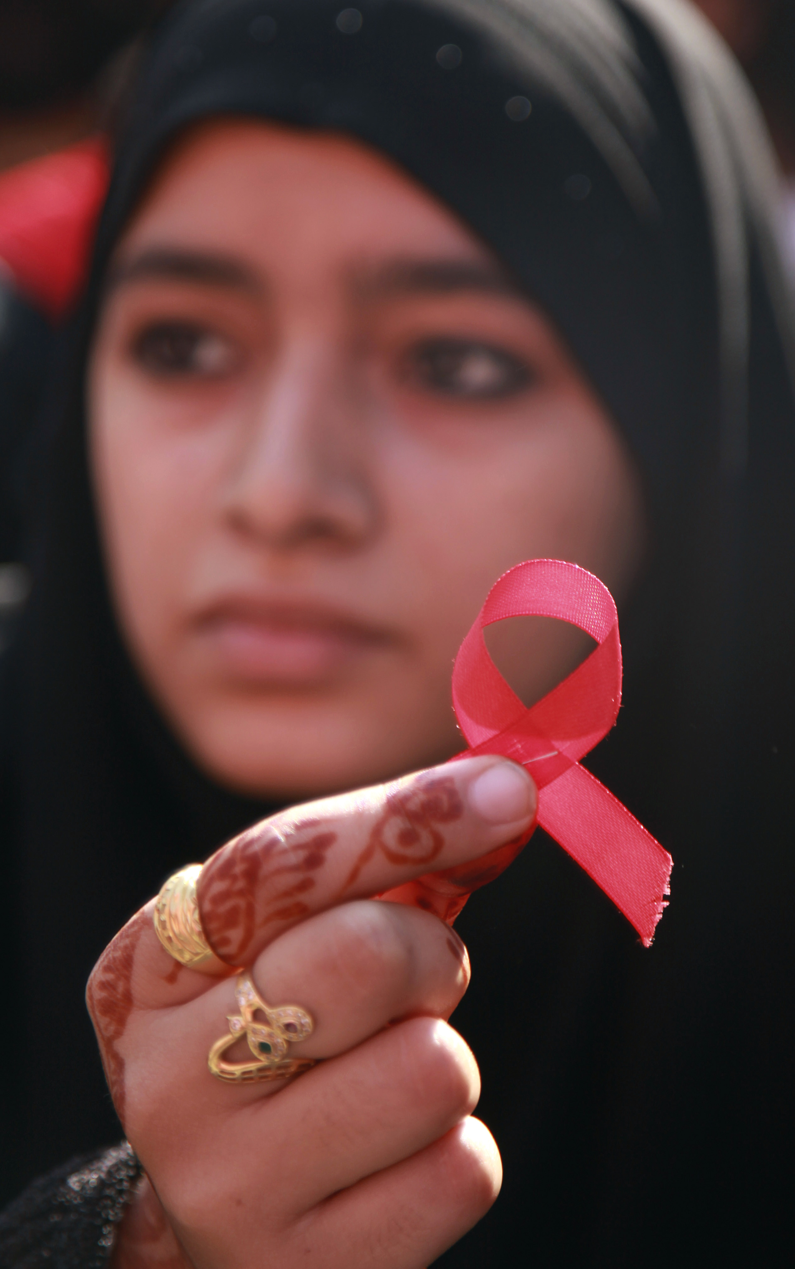 A college student displays a red ribbon, the symbol for AIDS awareness, at a rally to mark World AIDS Day in Jammu, India, Wednesday, Dec. 1, 2010.