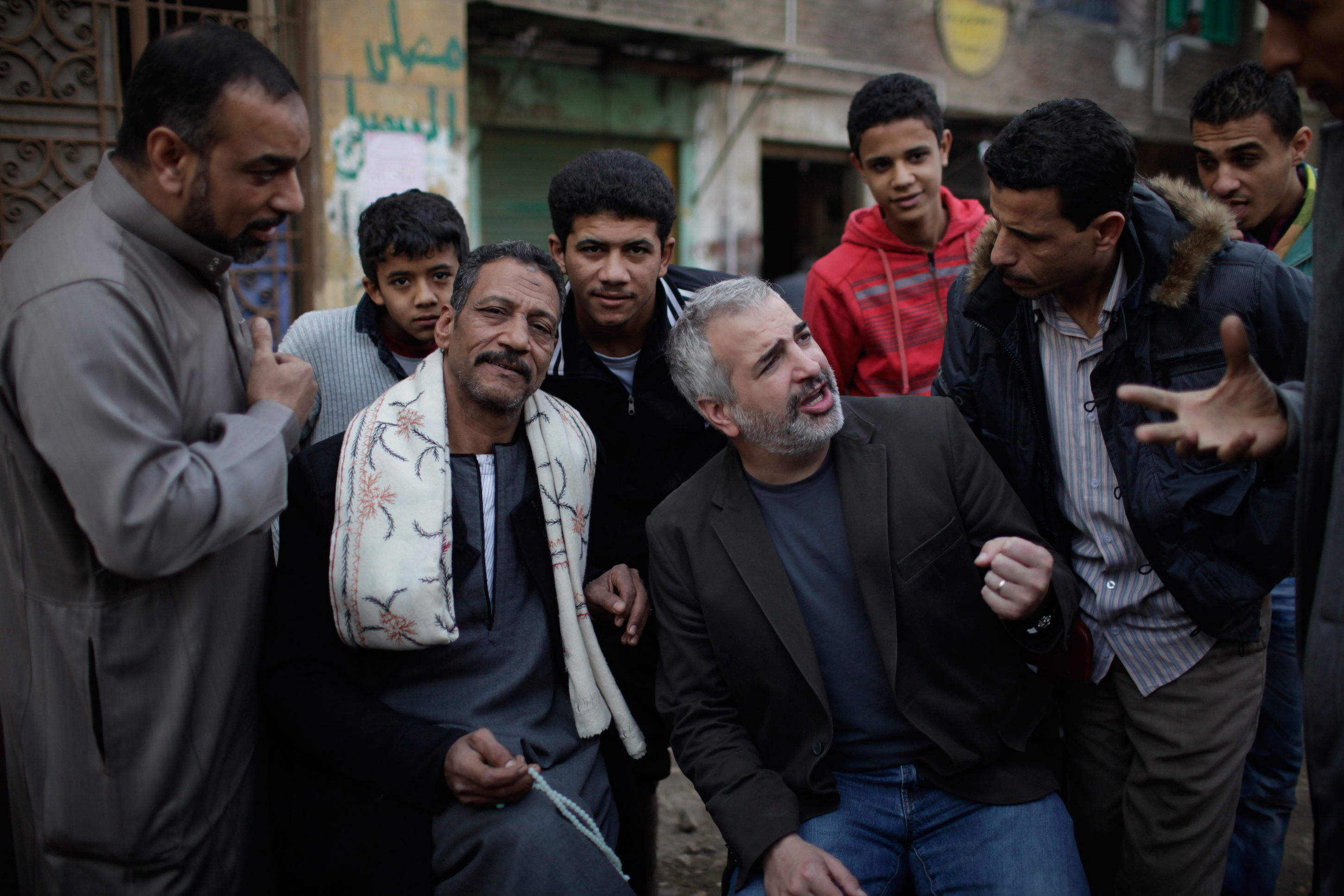 In this Feb. 2, 2011 photo provided by The New York Times, Times journalist Anthony Shadid, middle right, interviews residents of Embaba, a lower class Cairo neighborhood, during the Egyptian revolution.