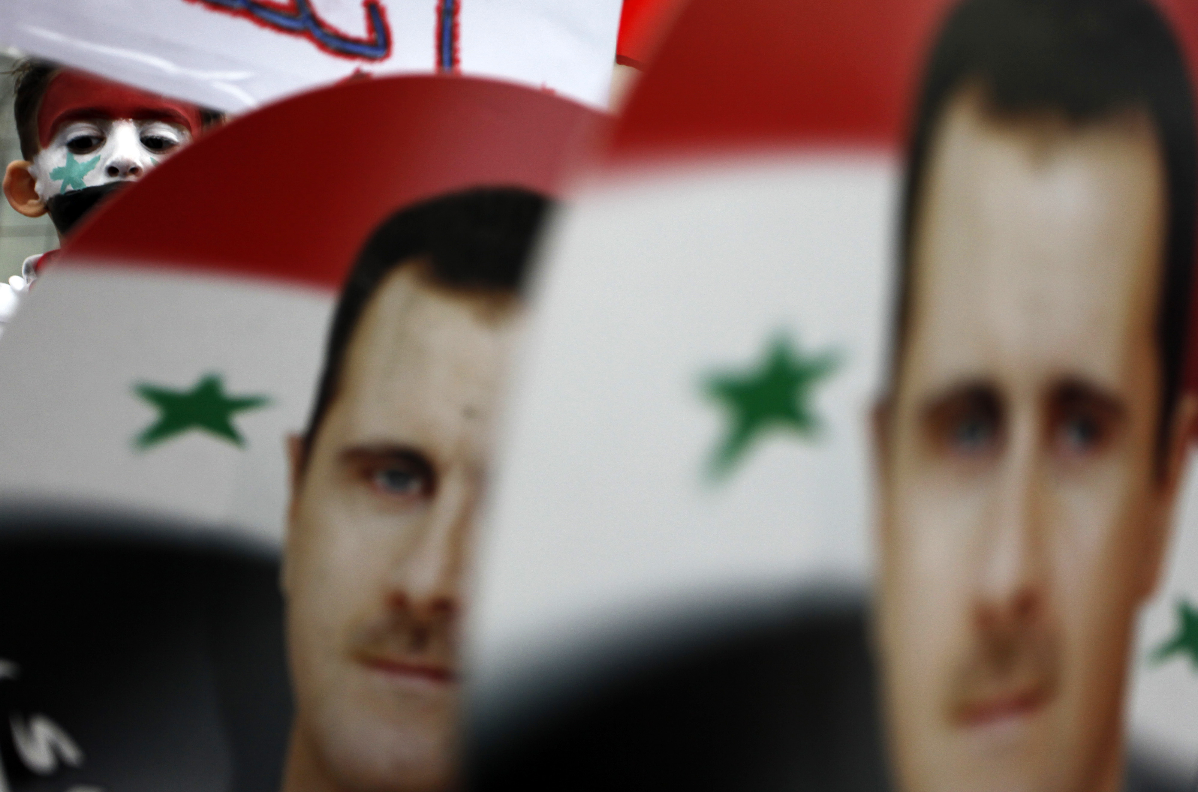 A Young Syrian immigrant is seen behind posters of Syrian President Bashar al-Assad as he takes part in a peaceful rally in Sofia, Bulgaria, in support of the Syrian President and the reforms carried out in Syria, during a rally Sunday, April 17, 2011.