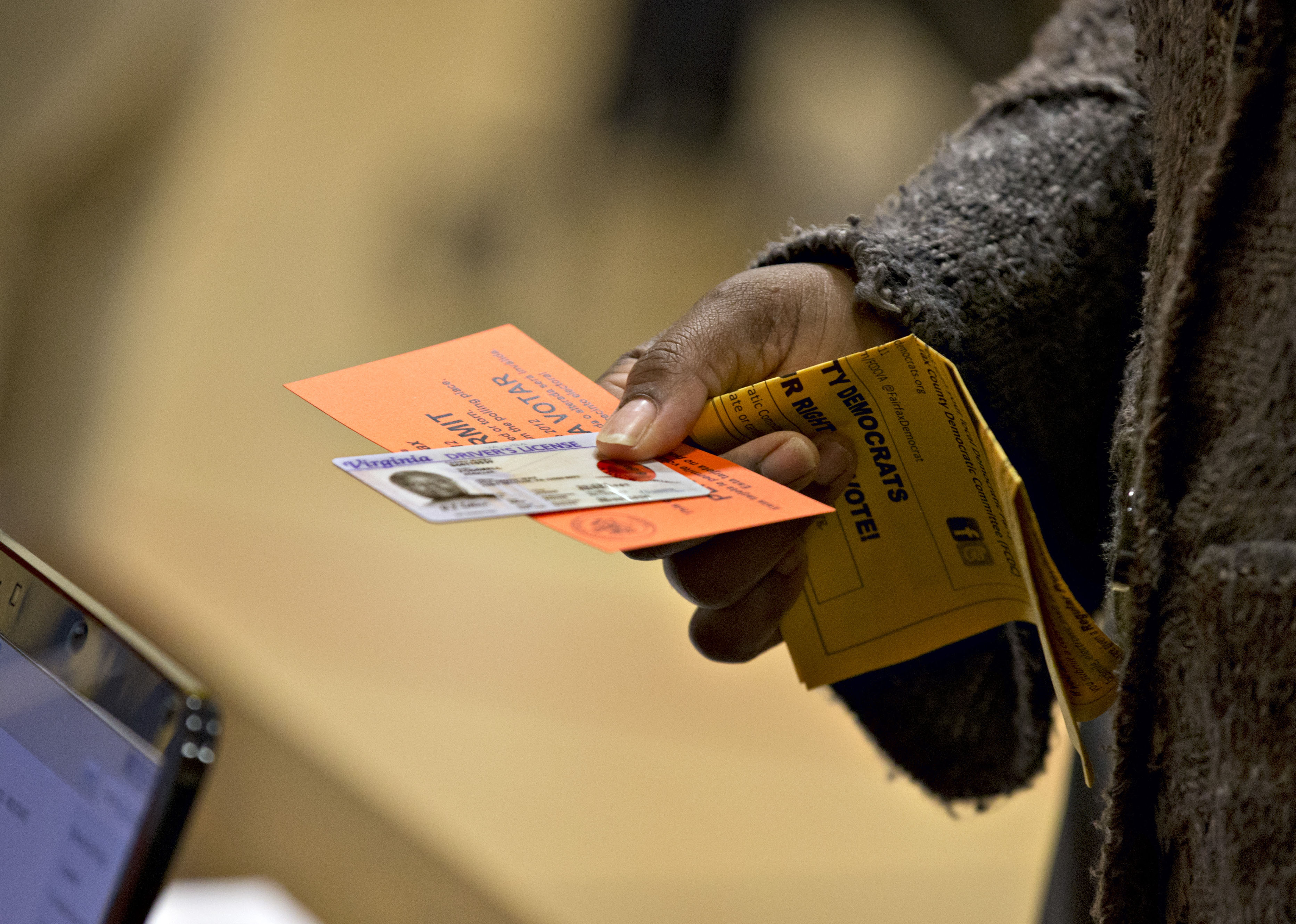 In this Nov. 6, 2012 file photo, a voter holds their voting permit and ID card at the Washington Mill Elementary School near Mount Vernon, Va.