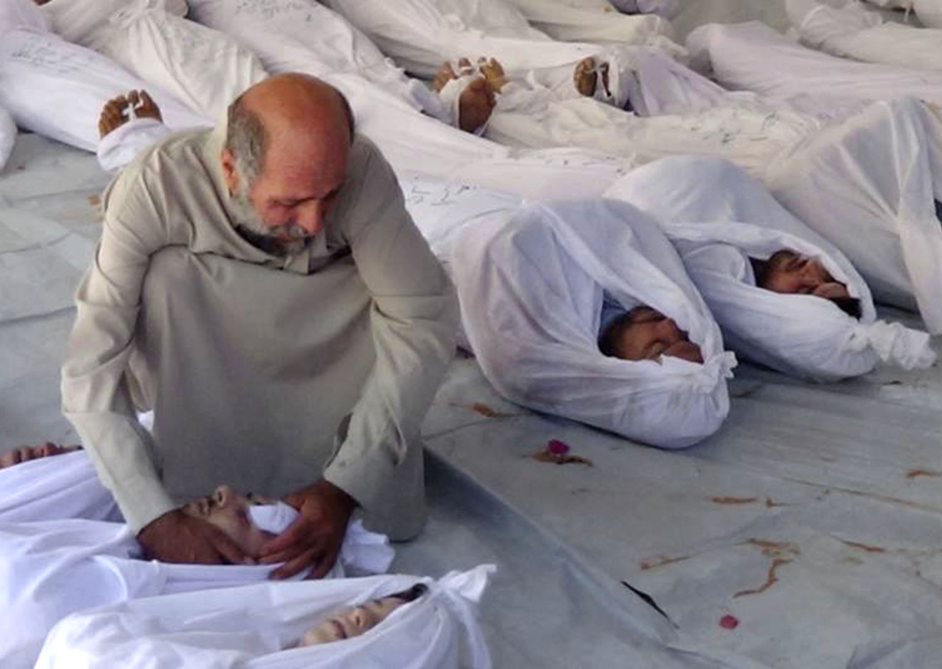 This citizen journalism image provided by the Media Office Of Douma City which has been authenticated based on its contents and other AP reporting, shows a Syrian man mourning over a dead body after an alleged poisonous gas attack fired by regime forces, according to activists, in Douma town, Damascus, Syria, Wednesday, Aug. 21, 2013. (AP Photo/Media Office Of Douma City)