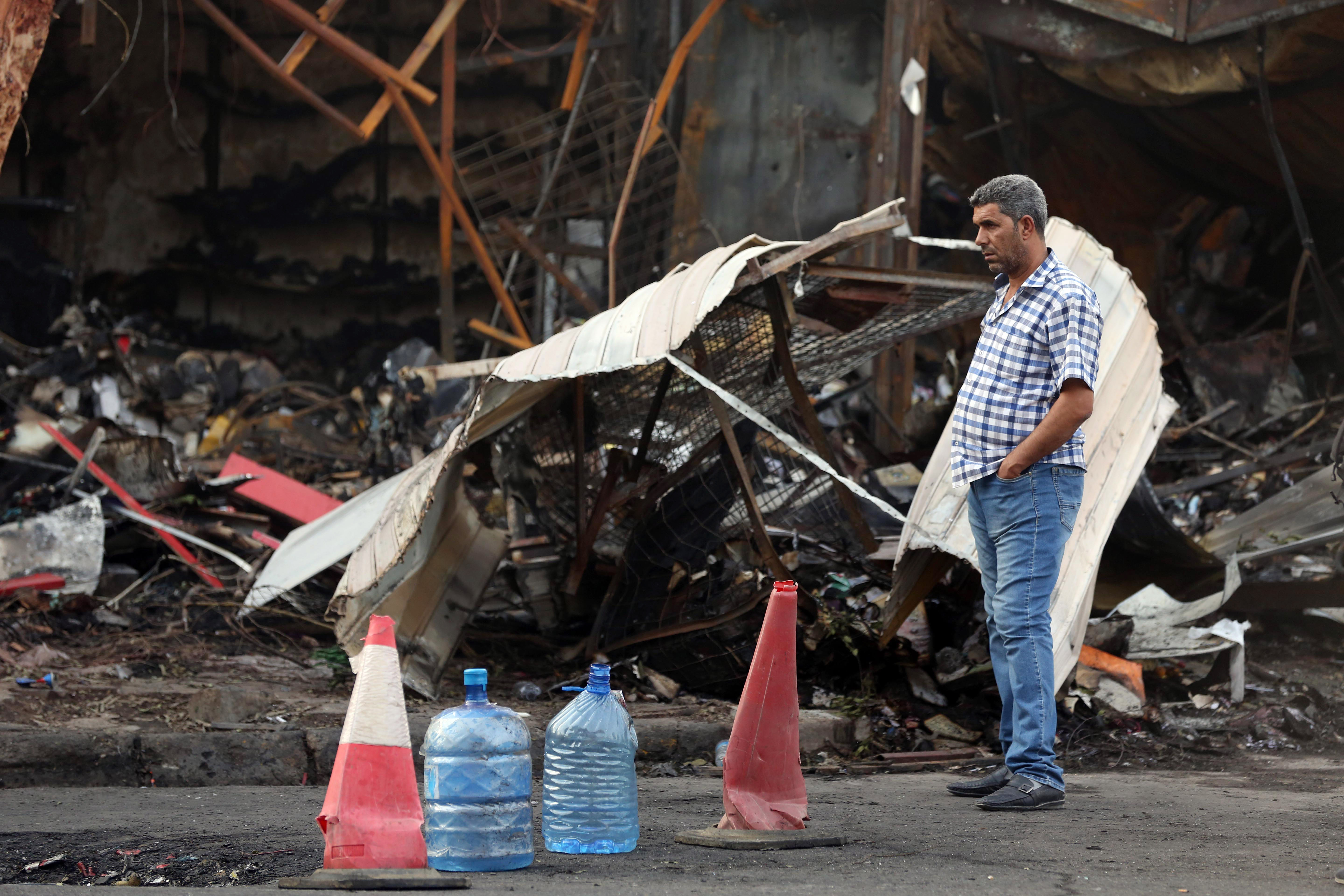 An Iraqi man inspects the site of a car bomb attack near a restaurant in central Baghdad's busy commercial Karradah neighborhood, Iraq, Friday, July 25, 2014. Police officials say a double car bombing on Thursday night took place in Karradah neighborhood in central Baghdad has killed and wounded scores of people, hours after lawmakers elected the country's new president. (AP Photo/Hadi Mizban)