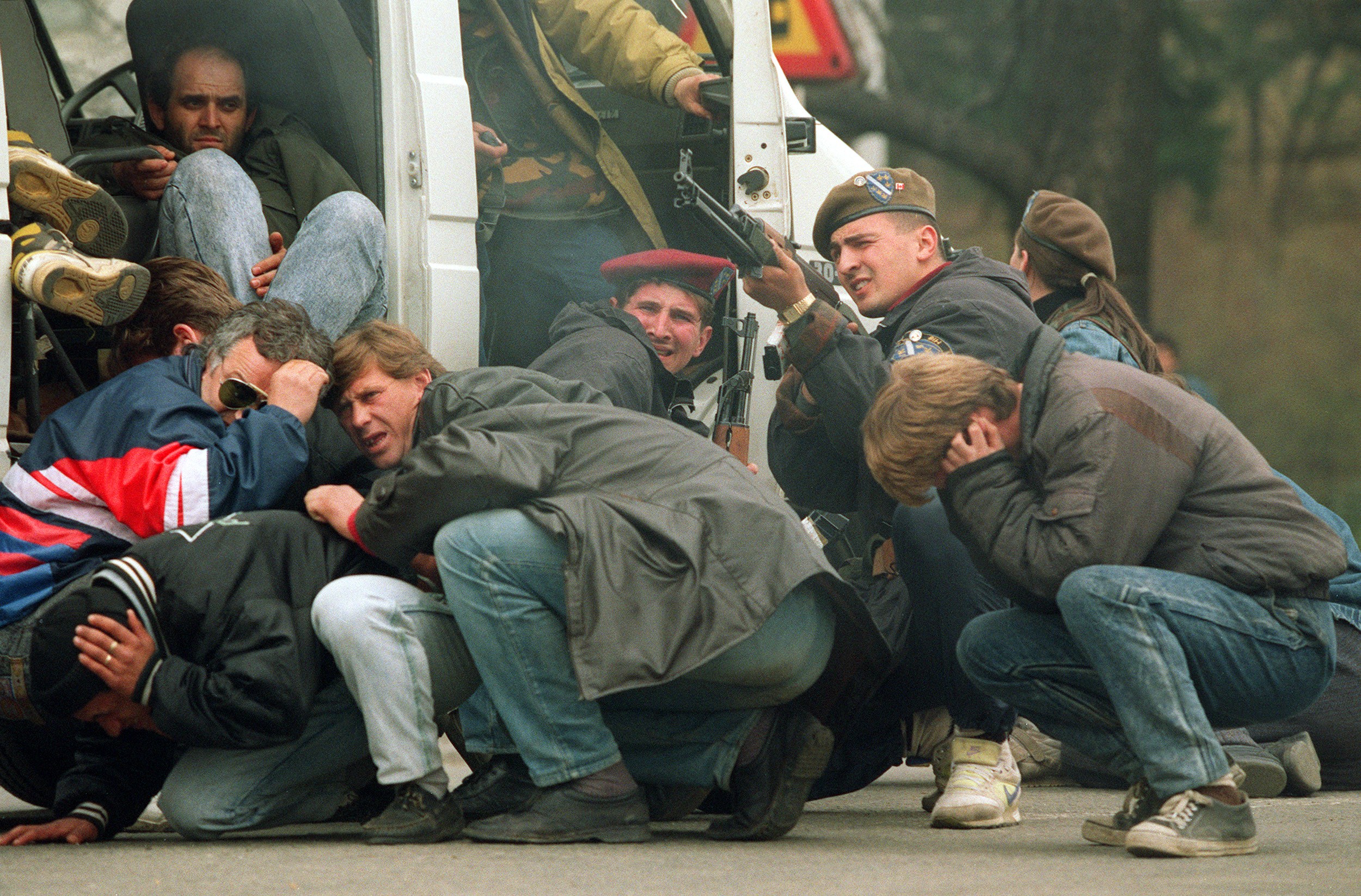 A Bosnian special forces soldier returns fire 06 April 1992 downtown Sarajevo as he and civilians come under fire from Serbian snipers. The Serb extremists were shooting from the roof of a hotel at a peace demonstration of some of 30,000 people as fighting between Bosnian and Serb fighters escalated in the capital of Bosnia-Hercegovina.