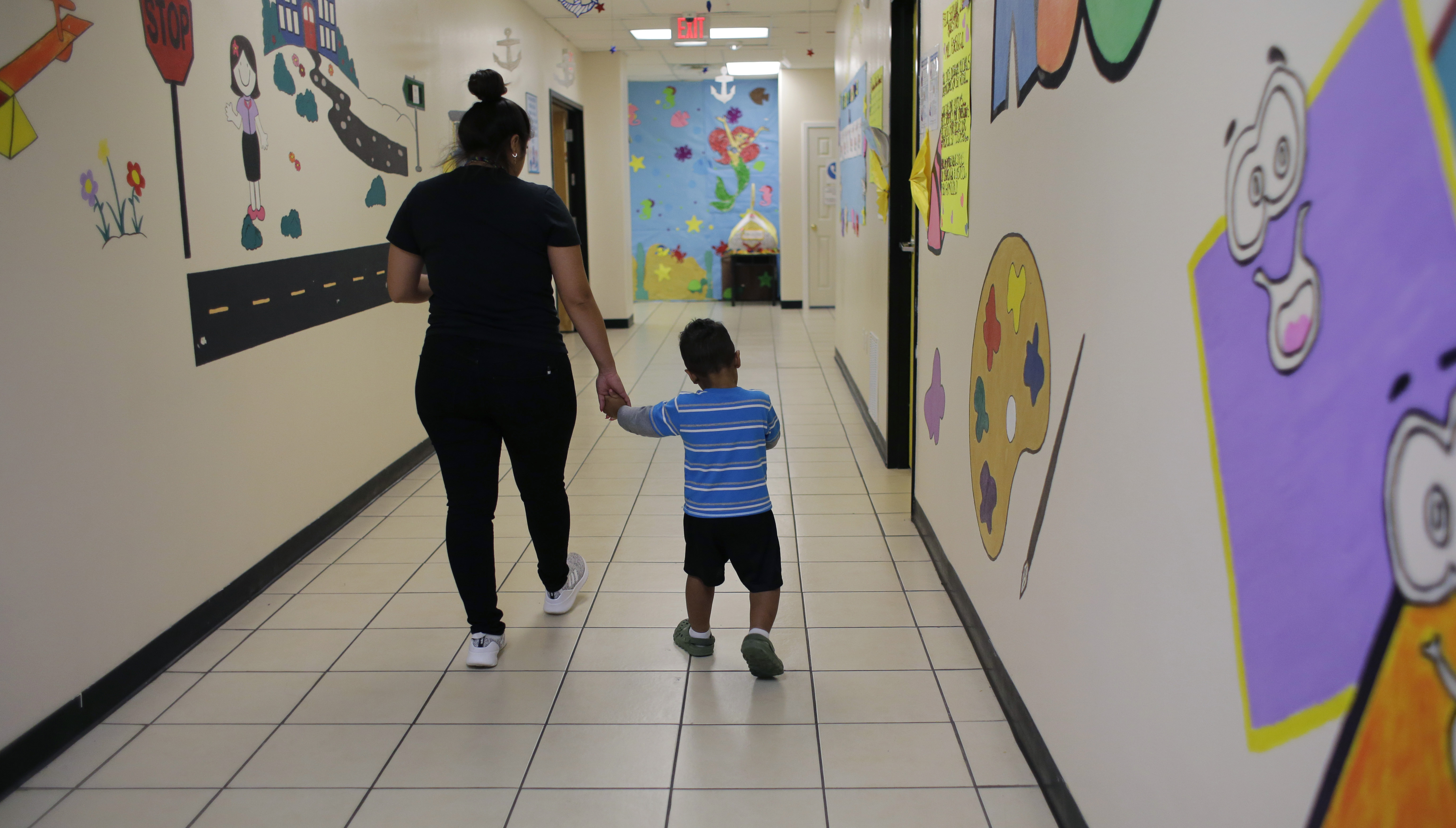 A young migrant boy walks with a Comprehensive Health Services caregiver at a "tender-age" facility, a facility for babies, children and teens, in Texas’ Rio Grande Valley, Thursday, Aug. 29, 2019, in San Benito, Texas. Sheltering migrant children is a booming business for Comprehensive Health Services, a Florida-based government contractor, as the number of children in government custody has swollen to record levels in the past two years.